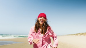 En kvinne løper på sandstrand ved havet.