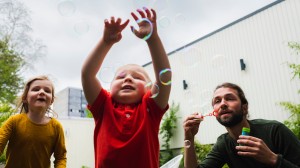 En far blåser såpebobler med de to barna sine