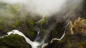 Fossefall og fjell omgitt av frodig natur