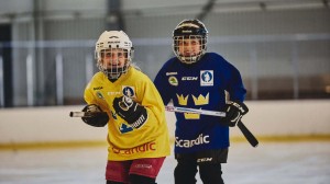 två barn i hockeyutrustning i rinken