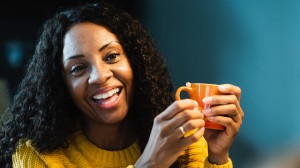 Kvinna i gul tröja med kaffekopp i handen