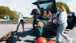 Familie pakker bilen på en solrik dag før tur – bilforsikring gir trygghet på reisen