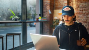 Ung man som sitter med sin dator på ett café