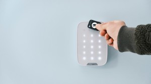 En hånd holder en svart nøkkelbrikke mot et elektronisk betjeningspanel. 