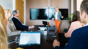 En kvinna i grå kavaj och orangea byxor som håller en presentation 