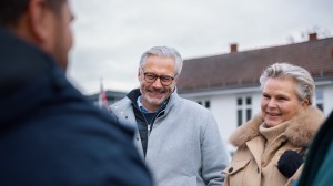 En mann og en dame smiler til en mann vi bare ser ryggen til.