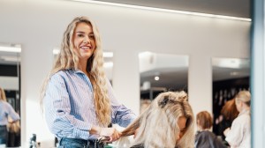 En smilende dame med mørkt hår og mørk lilla jakke