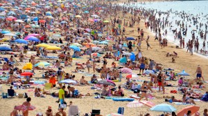 Sandstrand med mycket människor som solar och badar