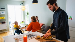 Far skjærer brød til frokosten. Resten av familien sitter rundt frokostbordet