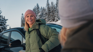 Kvinna med vandringskläder och blåsigt hår som står på ett berg