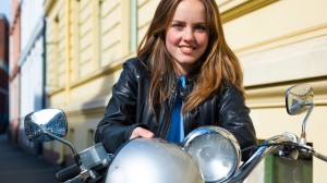 Ung tjej med hjälm på sin moped