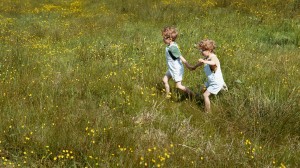 Illustrasjonsfoto grønn vurdering. To barn som leker i en blomstereng.