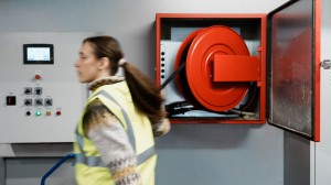 Ung dame i refleksvest som er på vei til å slukke en brann med brannslukningsapparat
