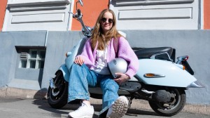 Tjej i rosa kofta som sitter framför sin moped