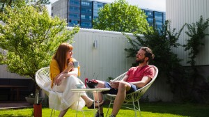 En kvinne og mann sitter ute i hagen og smiler og snakker sammen