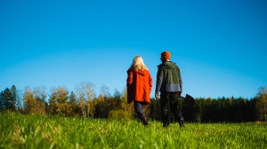 En kvinne og en mann går med ryggen til over et grønt jorde