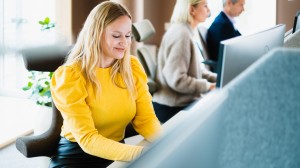 Kvinna i gul tröja framför dator