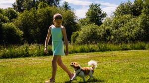 En jente går tur med en liten hund på en varm sommerdag