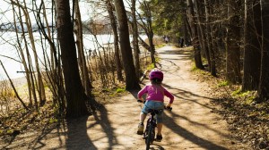 Flicka som cyklar på en skogsväg