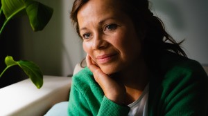 Kvinna i grön kofta som sitter i soffa