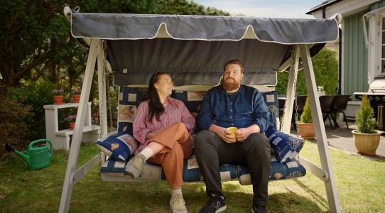 En kvinna och en man som sitter i en hammock och pratar